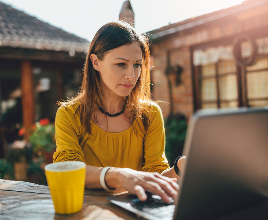 A US Expat woman working outside on computer in Europe.